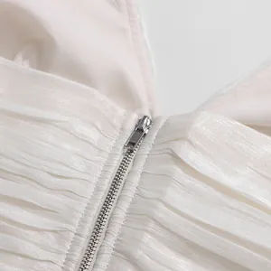 Detail of metallic zipper on white pleated French style sleeveless top with satin texture