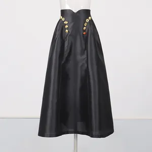 Detail des schwarzen Satin-Maxirocks mit dekorativen surrealistischen Goldknöpfen