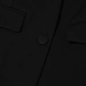 Close-up of the premium fabric texture and covered button on a black women's suit jacket