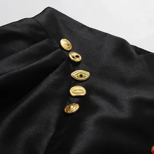 Detailansicht eines schwarzen Rocks mit hohen Bund und künstlerischen goldenen Knöpfen
