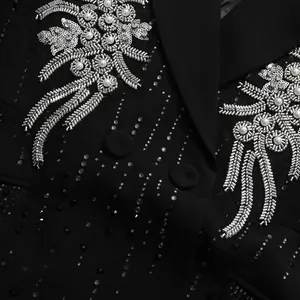 Detaillierte Nahaufnahme der Strass- und Perlenstickerei auf einem schwarzen Blazer