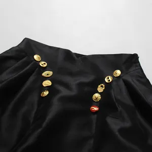 Detailansicht der dekorativen goldenen und roten Knöpfe am schwarzen High-Waist-Rock