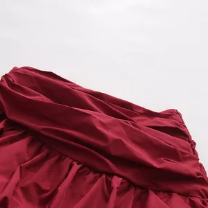 Dettaglio ravvicinato dell'elegante tessuto bordeaux arricciato su una gonna a pieghe.