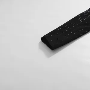 Makro-Detailansicht der funkelnden Strass-Verzierungen am Ärmel eines schwarzen Blazers