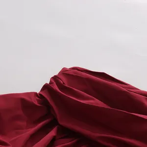 Dettaglio ravvicinato delle pieghe di una gonna bordeaux con trama di tessuto di lusso.