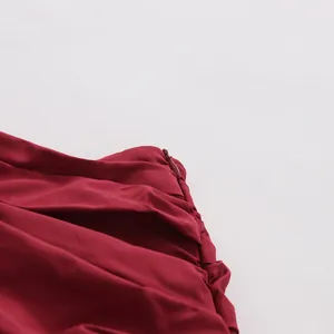 Dettaglio macro della zip invisibile e della trama a pieghe su una gonna bordeaux