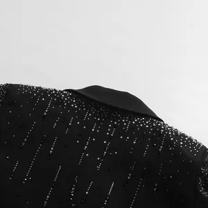 Nahaufnahme glitzernder Strassverzierungen auf einem schwarzen Blazer mit Reverskragen