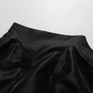 Detailansicht eines eleganten schwarzen Faltenrocks mit hoher Taille und Satin-Optik