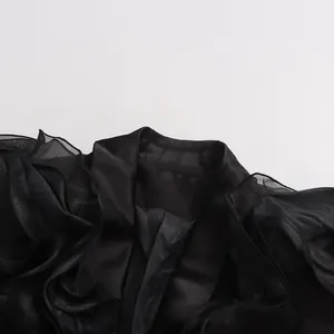 Nahaufnahme eines eleganten schwarzen Satin-Blazers mit gerüschten Organza-Ärmeln