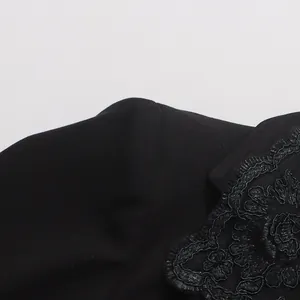 Close-up view of black suit jacket shoulder featuring intricate floral lace embroidery