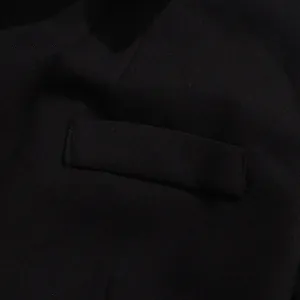 Macro detail of the high-quality stitching and pocket flap on a black slim-fit women's blazer.