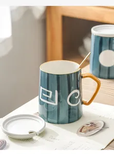 Detailansicht einer blau gestreiften Keramiktasse mit Deckel und goldenem Löffel