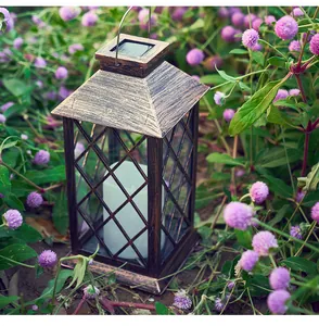 Detail of retro solar candle lantern with bronze finish in a flowering garden setting