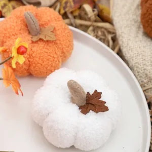 Decorative plush pumpkins in orange and white for Halloween and Thanksgiving decor.