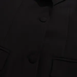 Detailed macro view of a black slim-fit commuter blazer jacket fabric and buttons