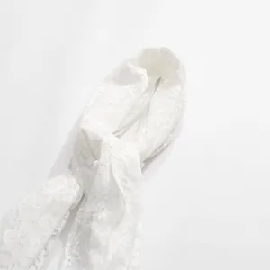 Dettaglio dell'elegante ricamo in pizzo floreale bianco su un top in stile francese