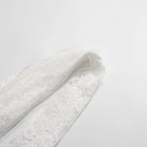 Primo piano del ricamo floreale e della trama delicata di una camicia in pizzo francese bianco