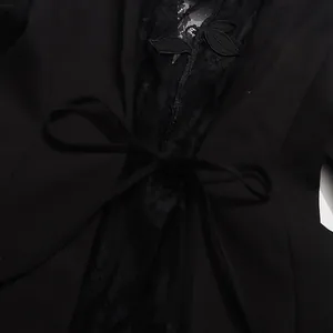 Close-up detail of black slim fit blazer with hollow-out lace embroidery and bow tie.