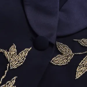 Detailed close-up of intricate gold bead embroidery on a navy blue luxury blazer