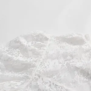 Dettaglio ravvicinato del ricamo floreale sul tessuto della camicia in pizzo bianco