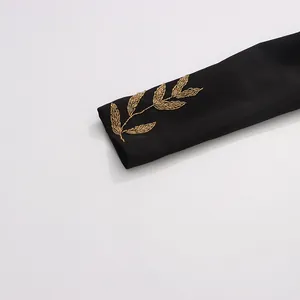 Close-up of intricate gold leaf bead embroidery on a black luxury blazer sleeve