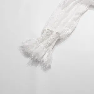 Primo piano della manica in pizzo bianco con polsino a balze svasato e ricamo floreale
