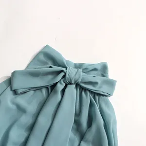 Detail of a light blue French blouse showing the elegant oversized bow accent.