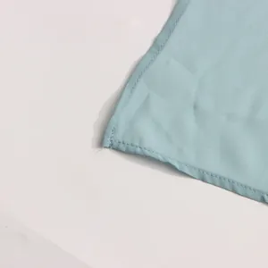 Close-up of the fine stitching and hem detail on a light blue French casual shirt.