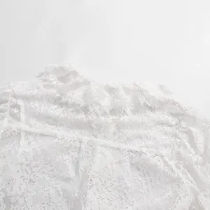 Dettaglio macro del ricamo in pizzo bianco e del colletto a balze della camicia