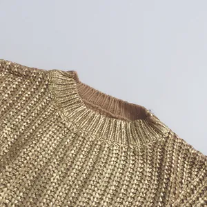 Detailansicht eines goldfarbenen Grobstrickpullovers mit einem gerippten Rundhalsausschnitt.