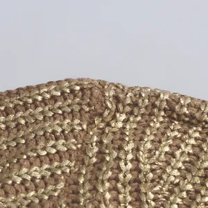 Detailreiche Nahaufnahme goldener Metallicfäden auf dem braunem Strickpulloverstoff