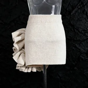 Detailed view of beige knitted mini skirt featuring layered ruffle side detail