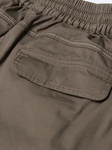Detailed close-up of elastic high waistband and cargo flap pocket on khaki skirt fabric