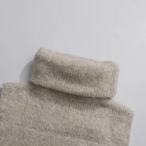 Close-up detail of a soft beige turtleneck knitted sweater showing warm yarn texture.