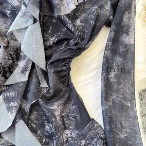 Dettaglio del top in rete tie-dye grigio con eleganti volant e stampa