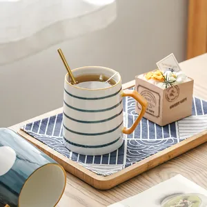 Minimalistische Keramiktasse im japanischen Stil mit Streifen und goldenem Löffel