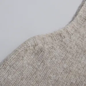 Close-up macro detail of the soft knit texture and shoulder line on a beige sweater