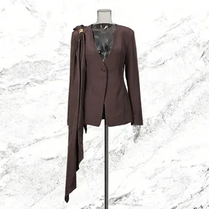 Close-up detail of a brown deep V-neck blazer featuring an asymmetric drape accessory