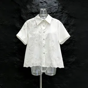 Dettaglio di camicia bianca a maniche corte con pizzo floreale e orlo con frange