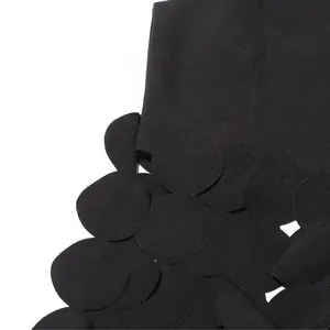 Macro detail shot of a black sleeveless top featuring artistic round petal fringe.
