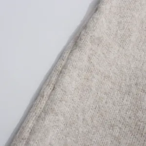 Detailed macro view of high-quality off-white knitted fabric showing soft texture.
