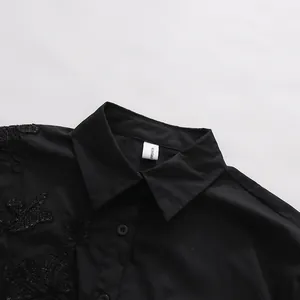 Primo piano del colletto della camicia nera con dettagli in pizzo ricamato.