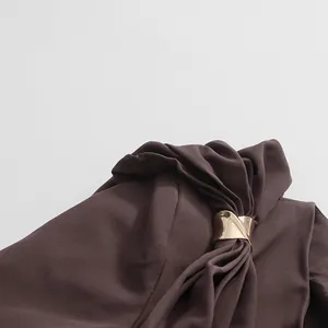 Close-up detail of the gold metallic buckle and draped fabric on a brown designer blazer