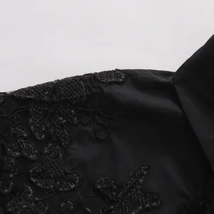 Primo piano del ricamo floreale in pizzo nero su una camicia a maniche corte da donna