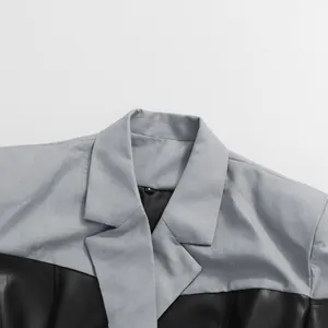 Detailopname van een minimalistische blazer met grijze stof en zwart kunstleren patchwork