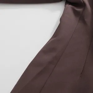 High-quality close-up of dark brown fabric and precise stitching on a women's tailored blazer