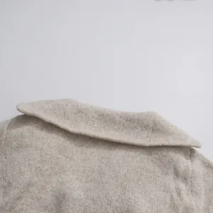 Detailed close-up of the beige knitted sweater collar showing the soft fabric texture.