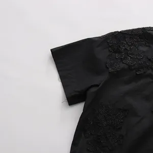 Dettaglio di camicia nera a maniche corte con raffinati ricami floreali in pizzo