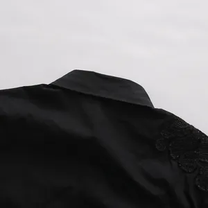 Dettaglio ravvicinato del colletto della camicia nera e ricamo in pizzo sulla spalla
