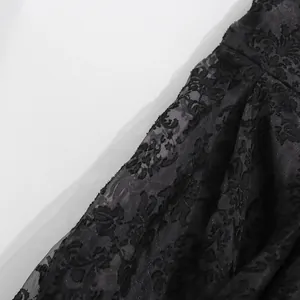 Dettaglio macro della rete in pizzo floreale nero su un'elegante gonna lunga jacquard